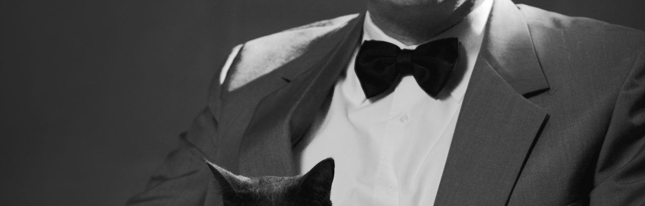 This is a picture of me sitting with October, our "blue" cat. Its in black and white and I look sort of like a pasty white super-villain from a James Bond film.