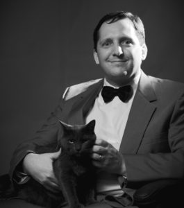 This is a picture of me sitting with October, our "blue" cat. Its in black and white and I look sort of like a pasty white super-villain from a James Bond film.